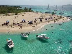 Wide-angle view of Icacos Beach with parasailers, jet skis, and high-rise hotels lining the shore.