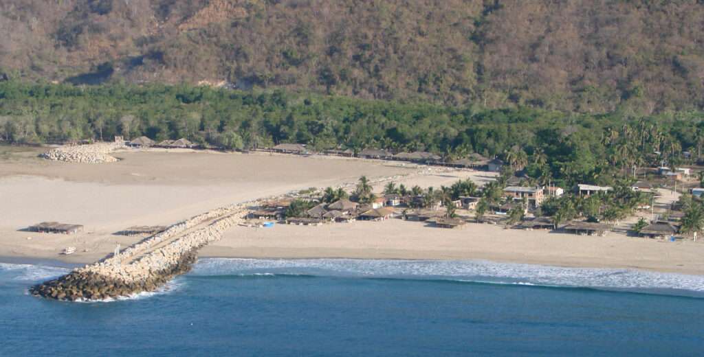 Cliffside view of Playa Cerro Hermoso with golden sands and panoramic Pacific horizon near Chacahua