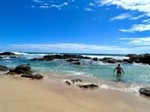 Tidal pools and rocky shoreline at Playa Agua Blanca with beachfront palapas and fresh oyster stands