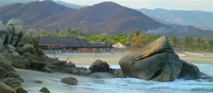 Towering white rock formation at Playa Roca Blanca with crashing waves and sunset glow near Chacahua