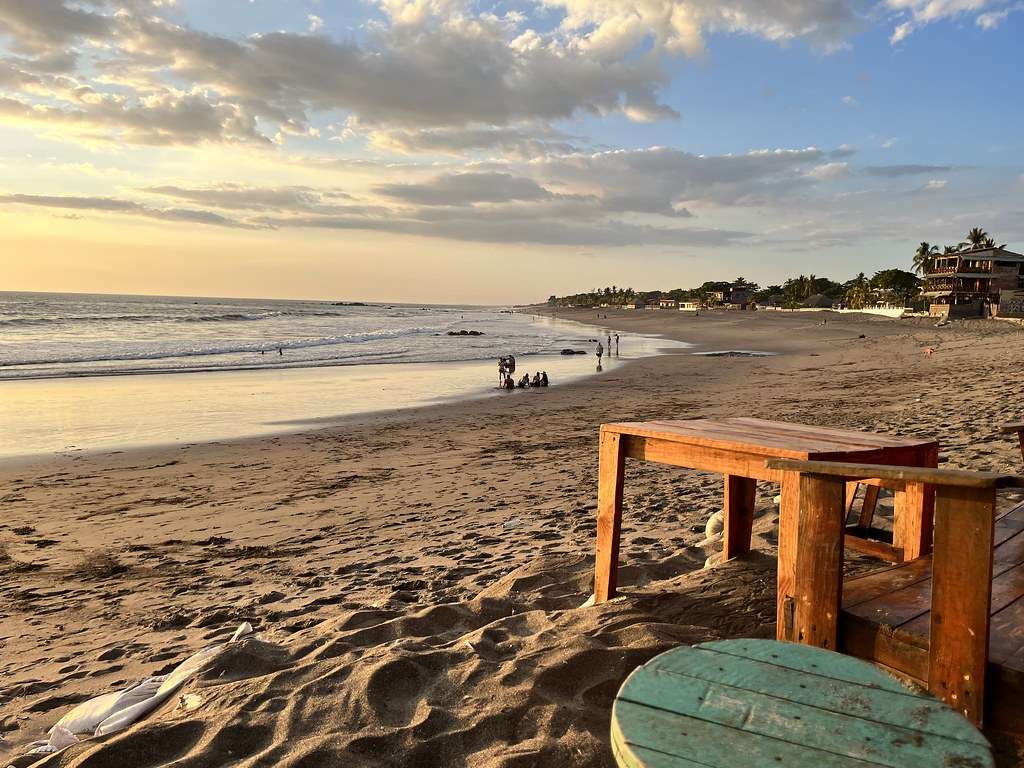Remote shoreline at Las Peñitas Beach with coastal vegetation, fishing boats, and open skies near Guerrero’s southern edge.